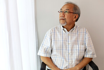 Unhappiness Asia man alone on wheelchair at home.