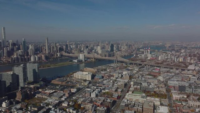 Slide and pan aerial footage of Queensboro Bridge. Various development in urban boroughs, low residential buildings and tall business skyscrapers. New York City, USA