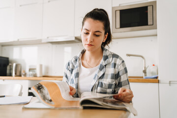 Young woman doing homework while sitting at table in kitchen
