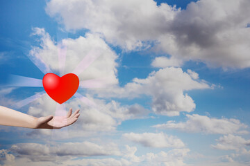 Hand holding heart shape with light ray on blue sky. Valentine decorative symbol concept. 3D rendering image.