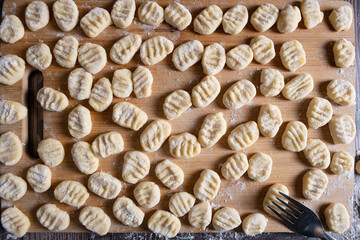 A raw traditional Italian gnocchia dish on a cutting board with a fork.