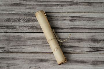 Antique brown scroll, tied with rope on a wooden background.