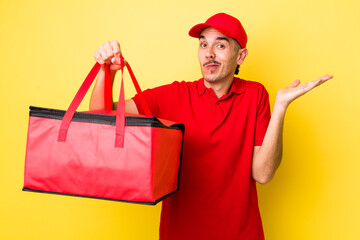 young hispanic man feeling puzzled and confused and doubting. delivery pizza concept