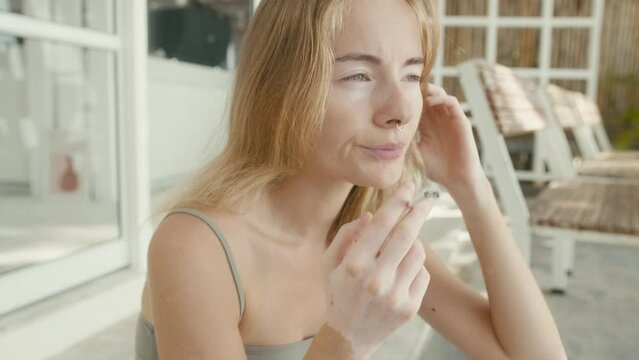 Pretty young woman with vitiligo pigmentation sits on the stairs and smokes 