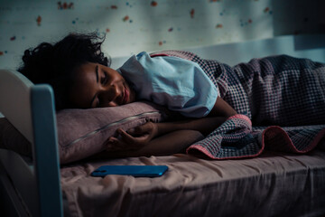 African teen girl sleeping near phone in her room
