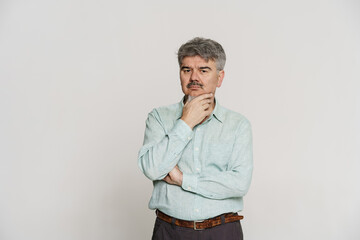 Mature puzzled man with grey beard posing and looking at camera