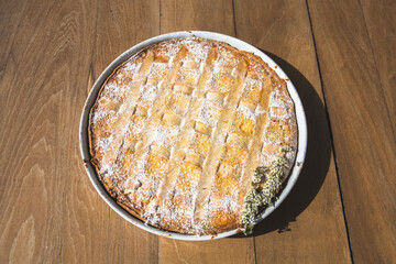 Close up shot of italian easter dessert, a home made Pastiera Napoletana cake, with ricotta cheese, candied peel, orange blossom water and cooked wheat. Typical from Naples. Wooden background.