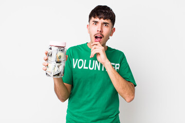 hispanic volunteer with mouth and eyes wide open and hand on chin. donations concept