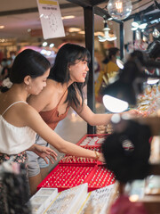 Two women inquiring about fashionable accessories and jewelries as well as haggling the prices at a...