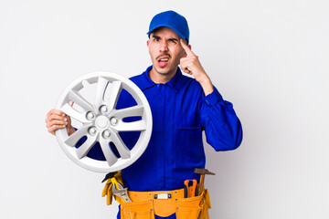 hispanic man feeling confused and puzzled, showing you are insane. car mechanic concept