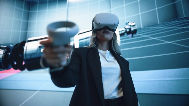Automotive Engineer Using a VR Software to Showcase Electric Motor and Vehicle Platform in Interactive Environment. Female Engineer Using Virtual Reality Headset and Controllers for Her Project.