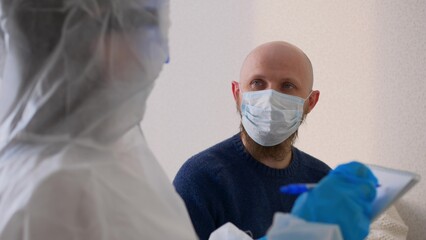 A middle-aged man in a mask sits at the doctor's office and complains of a sore throat and...