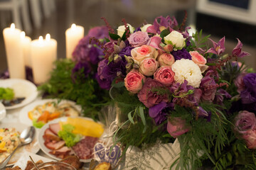 Festive served table for the bride and groom, decorated with flowers in vases, at a banquet, in a restaurant.