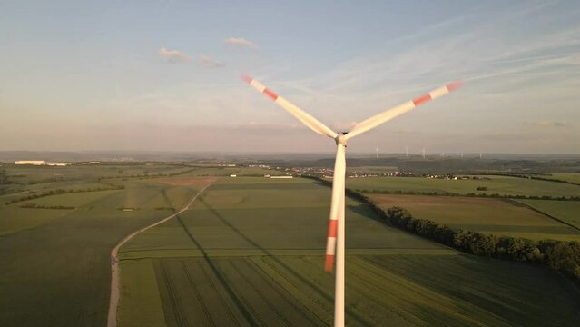 rising images of a spinning wind turbine in the endless green fields of the german eifel area