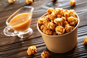 Caramelized popcorn in paper bucket on wooden table