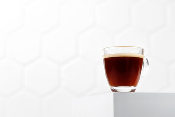 Espresso in glass cup on white podium and tile background. Aroma, ristretto. Mug of coffee. Minimalism. Copy space