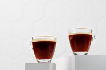 Two glass cups of coffee espresso on white podiums and tile background. Aroma, ristretto. Drink on podium. Minimalism. Copy space