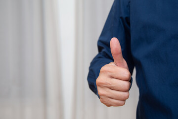 A young man' hand is displaying a thumbs up, indicating that he likes or approves of something