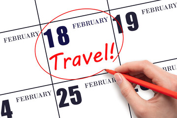 18th day of February. Hand drawing a red circle and writing the text TRAVEL on the calendar date 18 February. Travel planning. Winter month. Day of the year concept.