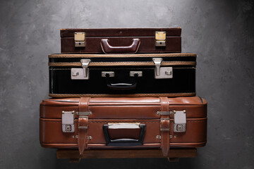 Heap of suitcases on wood shelf at wall. Old vintage suitcase
