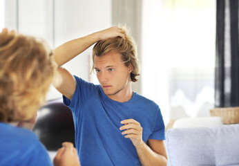 young man looking in the mirror,combing his hair,looking at problems on face