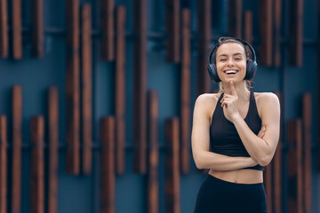 Fototapeta premium Girl with earphones standing, smiling, raising finger.