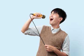 Portrait of young handsome Asian man singing a song with a microphone. happy and relax, enjoy the moment.
