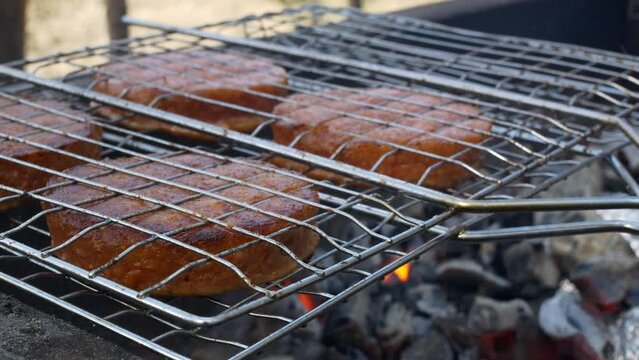 Close-up fried fatty cutlets for a burger on a grill. Vegetarian hamburger meat is grilled over charcoal, the smoke infuses the food with a delicious aroma. Picnic in the park with cooking on fire.