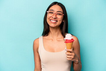 Young hispanic woman holding an ice cream isolated on blue background happy, smiling and cheerful.