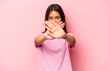 Young hispanic woman isolated on pink background doing a denial gesture