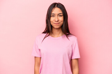 Young hispanic woman isolated on pink background blows cheeks, has tired expression. Facial...