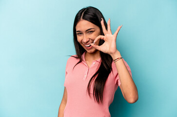 Young hispanic woman isolated on blue background cheerful and confident showing ok gesture.