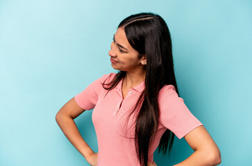 Young hispanic woman isolated on blue background laughs happily and has fun keeping hands on stomach.