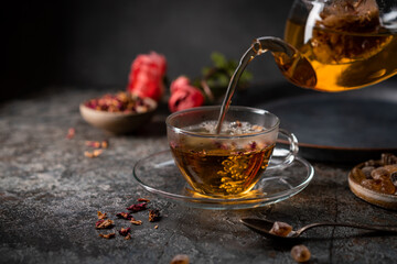 herbal flower tea from the petals of rose in a glass cup on dark gray background