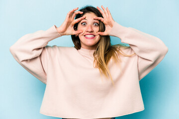 Young caucasian woman isolated on blue background keeping eyes opened to find a success opportunity.