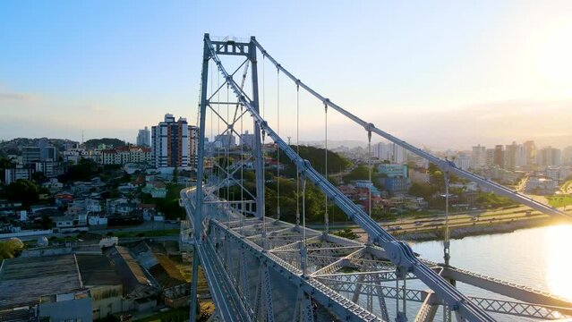 Aerial drone scene of suspension bridge hercilio luz revealing its structure and the city in the background in sunset