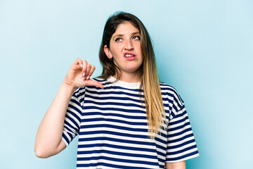 Young caucasian woman isolated on blue background showing a dislike gesture, thumbs down. Disagreement concept.