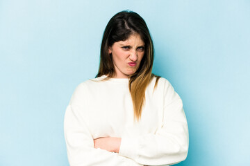 Obraz premium Young caucasian woman isolated on blue background frowning face in displeasure, keeps arms folded.