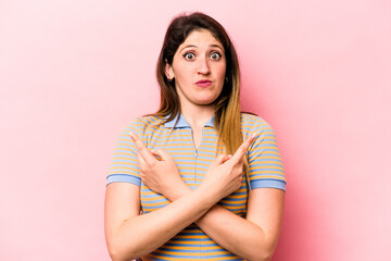 Young caucasian woman isolated on pink background points sideways, is trying to choose between two options.