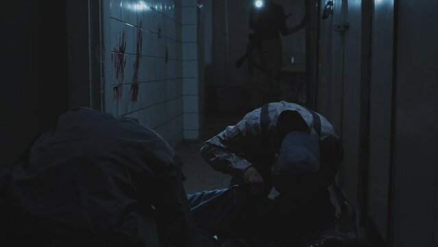 Low angle of two zombies feeding on dead body, then spotting and following female soldier with shaved head holding flashlight, inspecting dark and creepy abandoned building