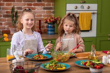 Children In Pyjamas Making Pancakes In Kitchen At Home Following Recipe On Digital Tablet