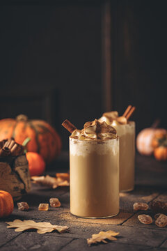 Autumn pumpkin spice latte with whipped cream and cinnamon on dark background