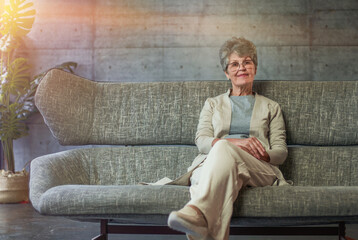 Smiling middle aged mature grey haired woman looking at camera, happy old lady in glasses posing at home indoor