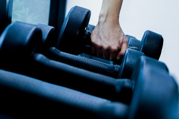 Fototapeta na wymiar Close up of hand holding dumbbell in fitness or gym. Concept of exercise, healthy and lifestyle.