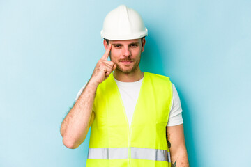 Young laborer caucasian man isolated on blue background pointing temple with finger, thinking, focused on a task.