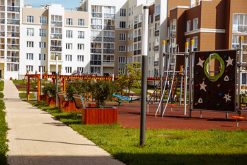 Empty a new modern playground in the courtyard of multi-storey residential buildings on a sunny summer day.
