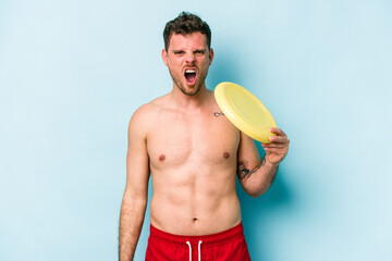 Young caucasian man playing with frisky isolated on blue background screaming very angry and...