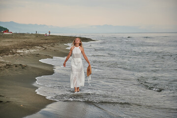 Fototapeta na wymiar a girl in a white dress on the sea looks into the sky