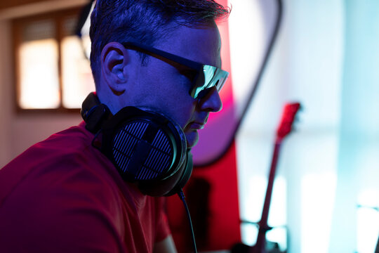 Musician and producer wears sunglasses to tune into the vibe while working with focus at his music home studio