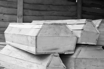 Black and white photo of wooden coffin against background of other wooden coffins as symbol of death and burial of person in coffin or several people in several coffins